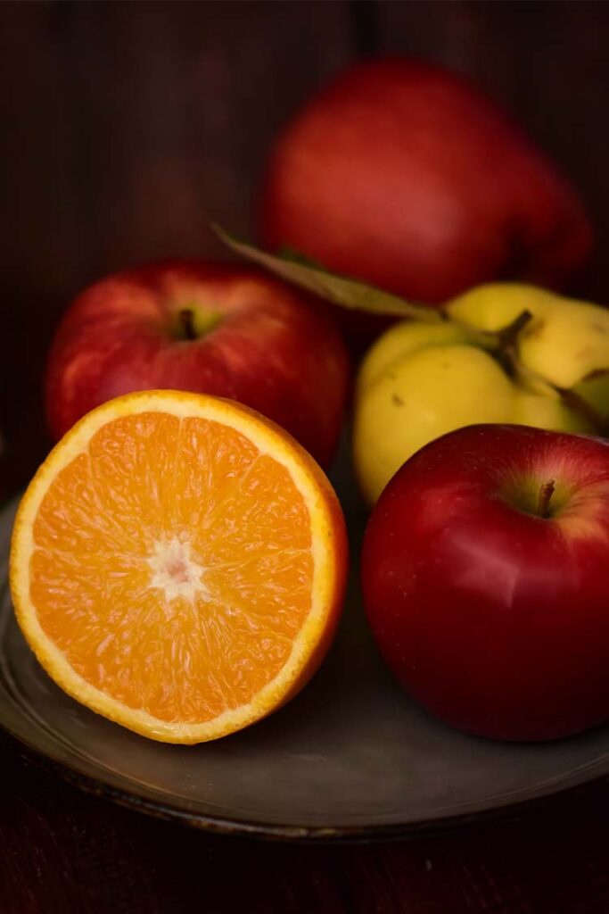 a plate of fruit with a half of an orange